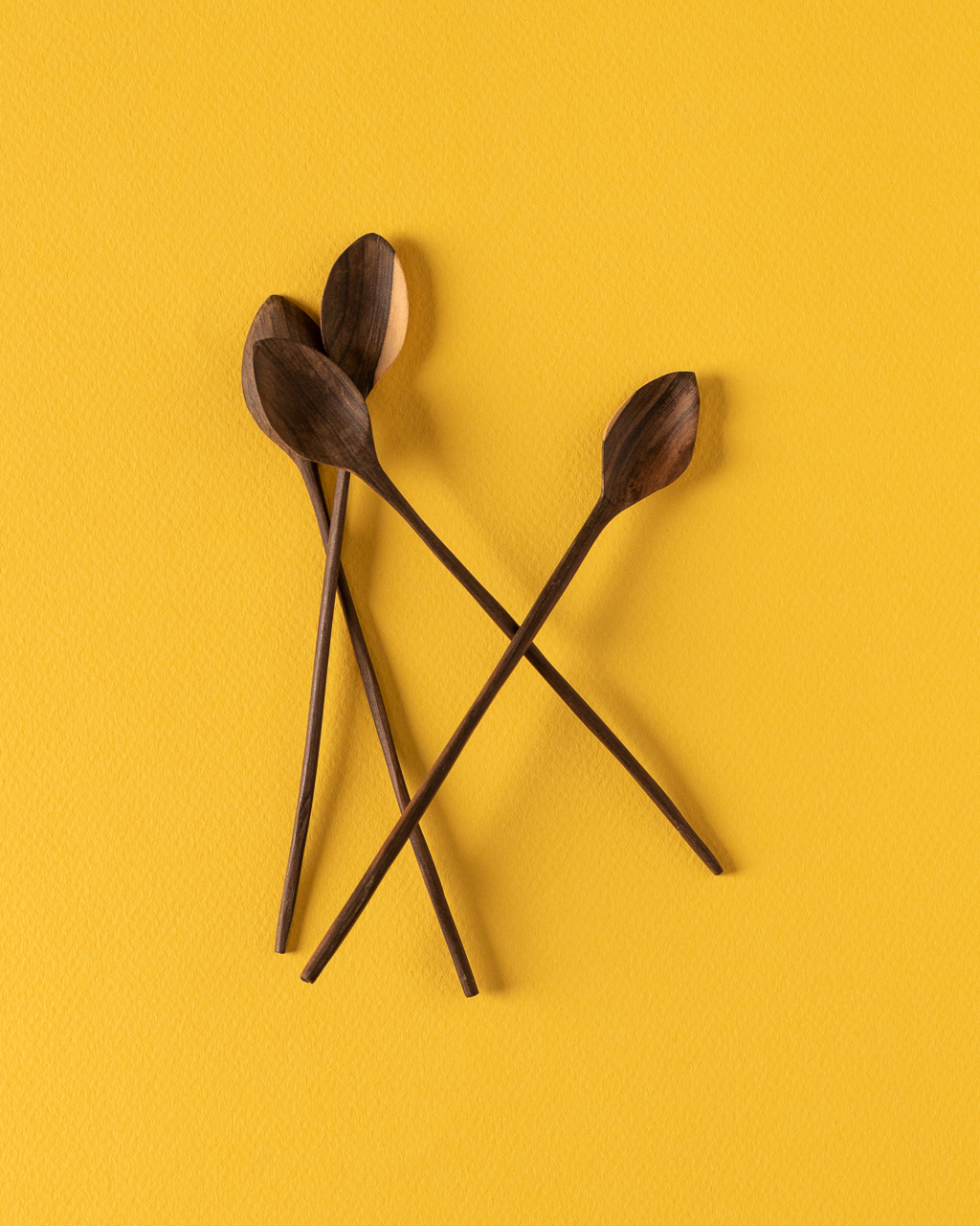 Tossed wooden spoons on yellow by Jose Barrios